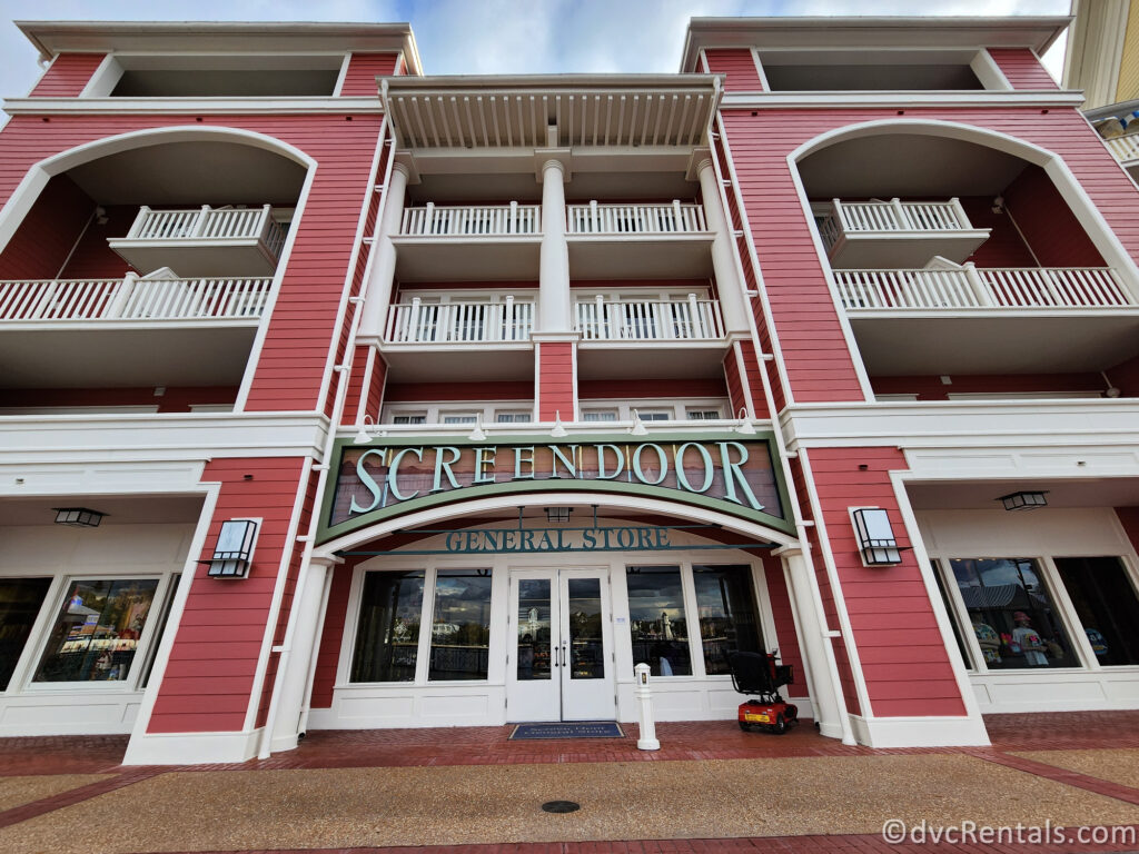 Exterior of the Screen Door General Store at Disney's Boardwalk Villas. The pink building has green wire letters above the glass doors.