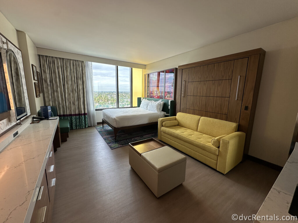 Studio layout featuring a yellow couch and a queen-sized bed.