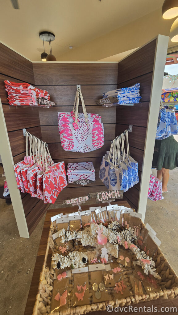 A display of tote bags and recycled conch jewelry.