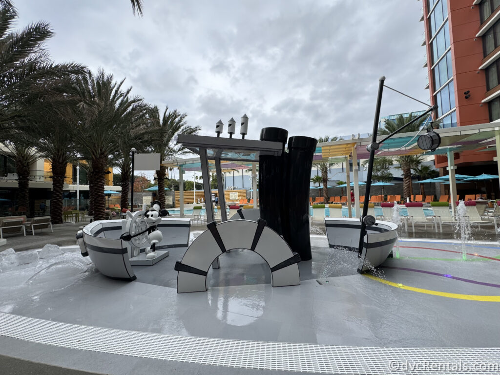 Steamboat Willie-themed water play area at the Villas pool. A black and white Steamboat Willie statue stands atop a black and white boat.