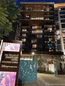 Large Hotel at night with lights coming from all the rooms. The brown sign in the front of the building reads "The Villas at Disneyland Hotel Discovery Tower."