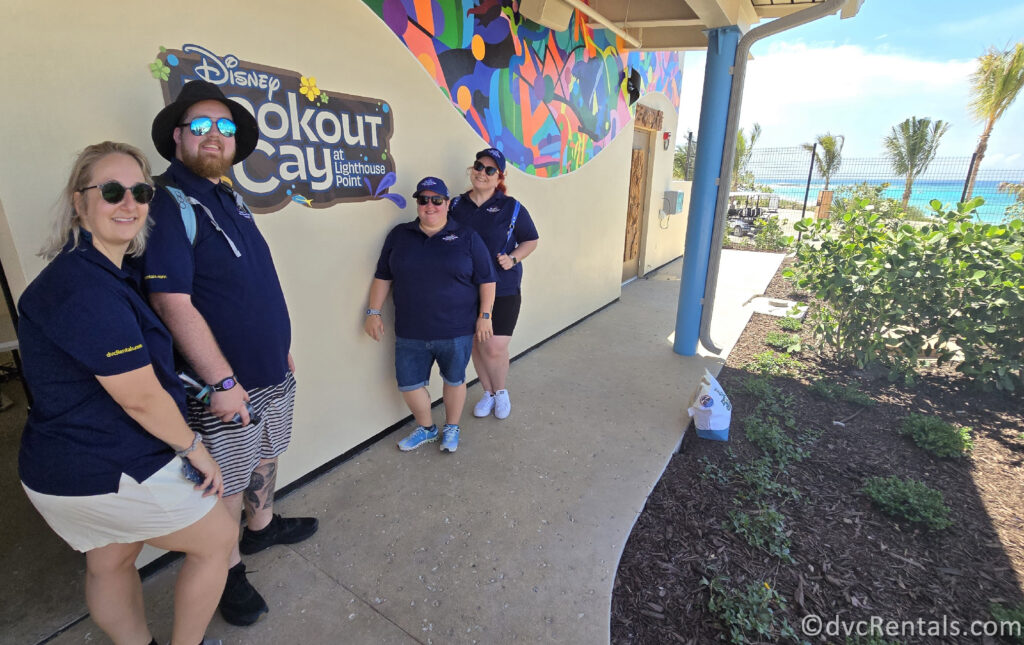 Team Members Kristen, Lindsay, Nick, and Cassie standing in front of a wall with a blue sign that reads "Disney Lookout Cay at Lighthouse Point".