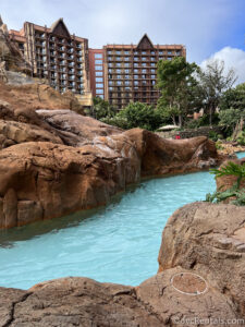 Lazy River between brown rocks at Aulani with the building in the background.