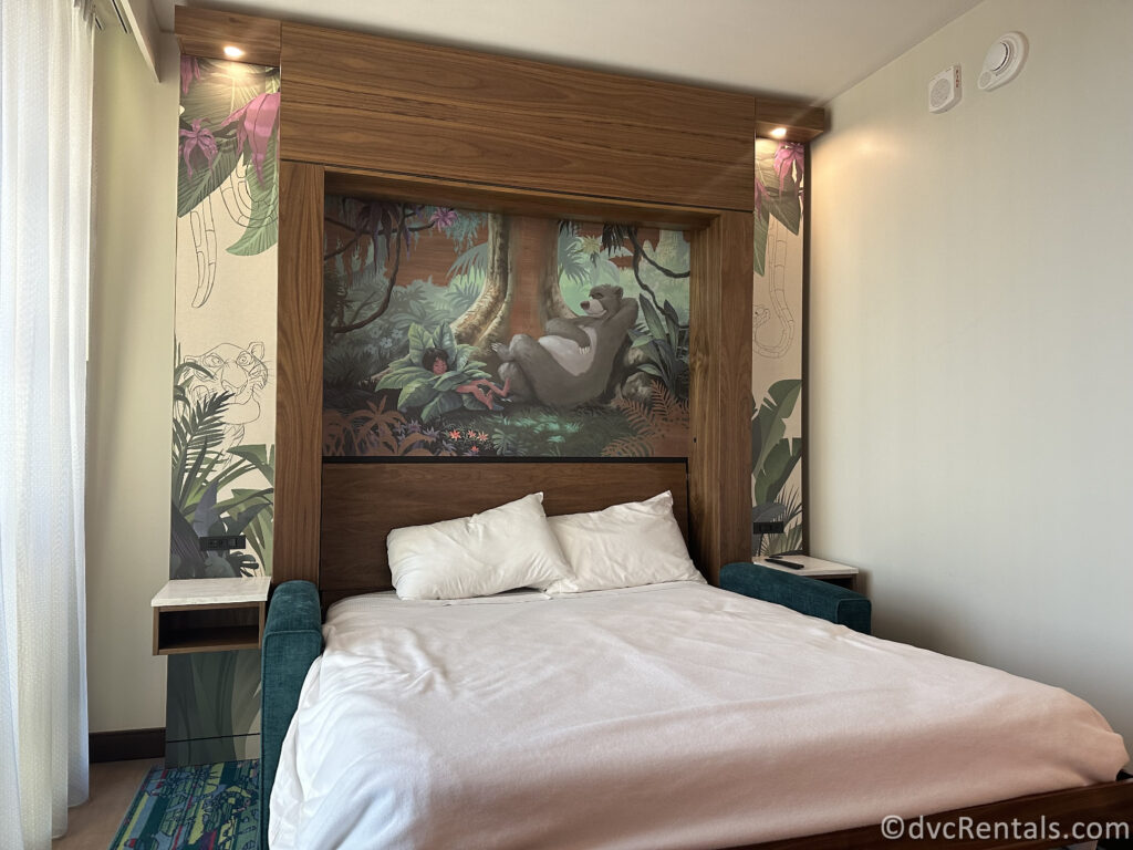 Pull-down queen-sized bed in the duo studio. There is a mural featuring Baloo and Mowgli from the Jungle Book above the bed.