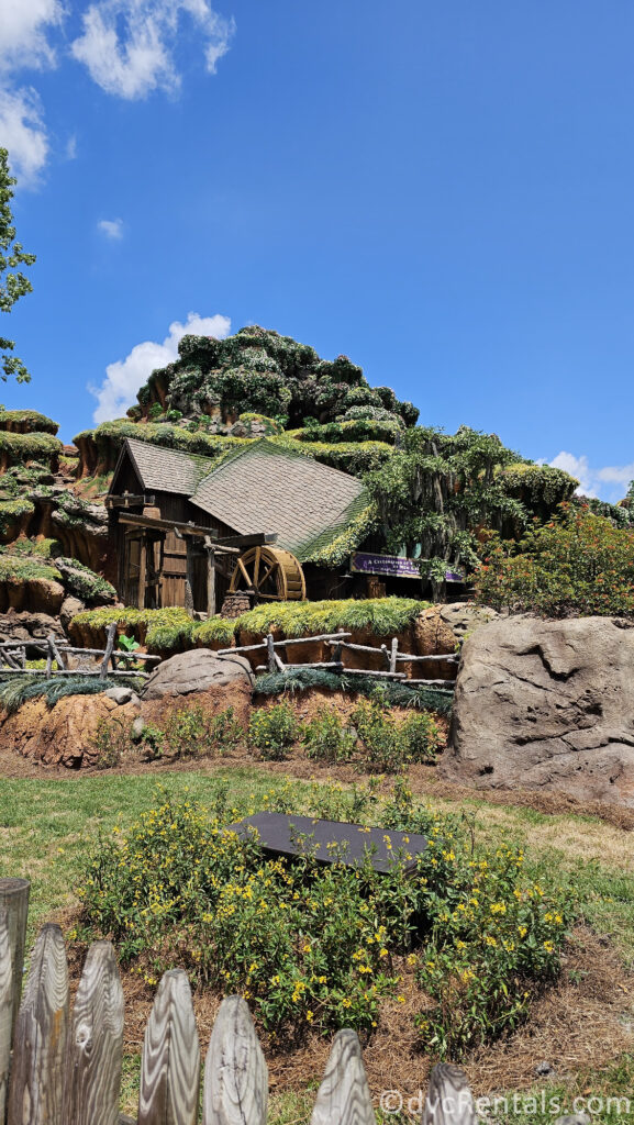 Exterior of Tiana's Bayou Adventure. Greenery and rocks cover a large hill.