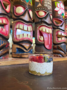 Chia Pudding topped with fruit sitting in front of Tiki Statues at Disney's Polynesian Resort.