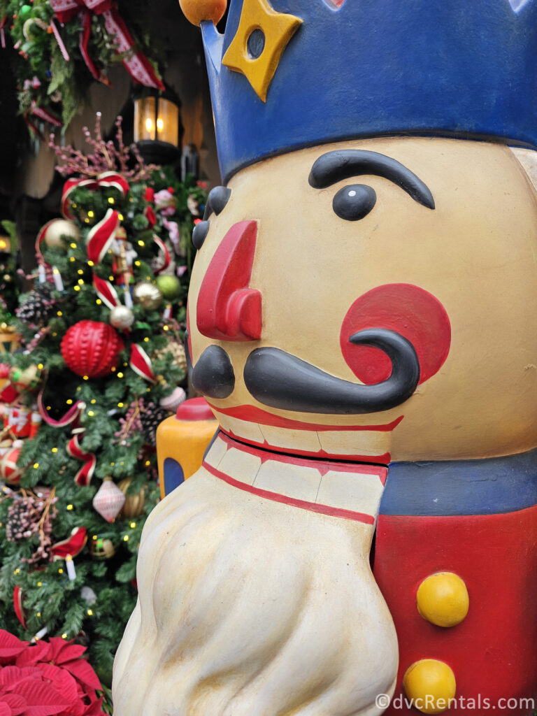 Nutcracker statue standing next to a Christmas Tree in the Germany pavilion at Epcot.