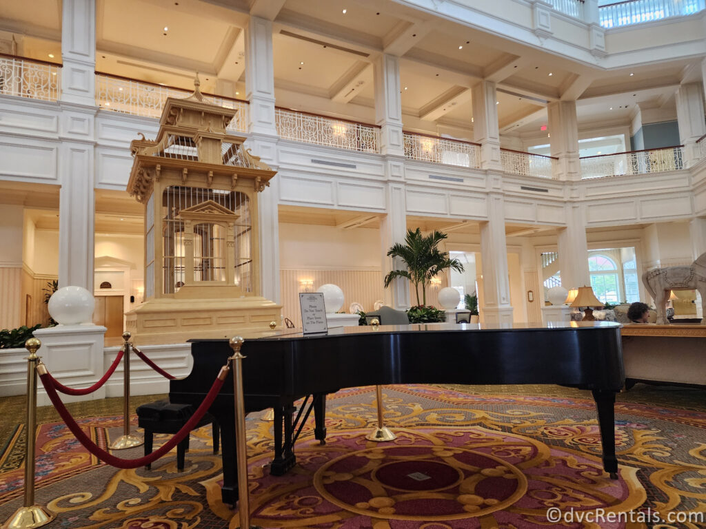 Grand Piano in the lobby at Disney's Grand Floridian. There are white columns around the room, and the Piano sits on a colorful, ornate carpet.