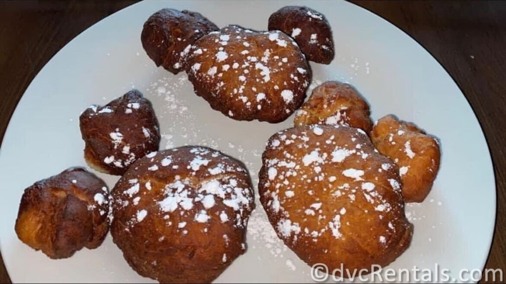 Mya's Homemade Beignets in the shape of Mickey Mouse heads covered in powdered sugar.