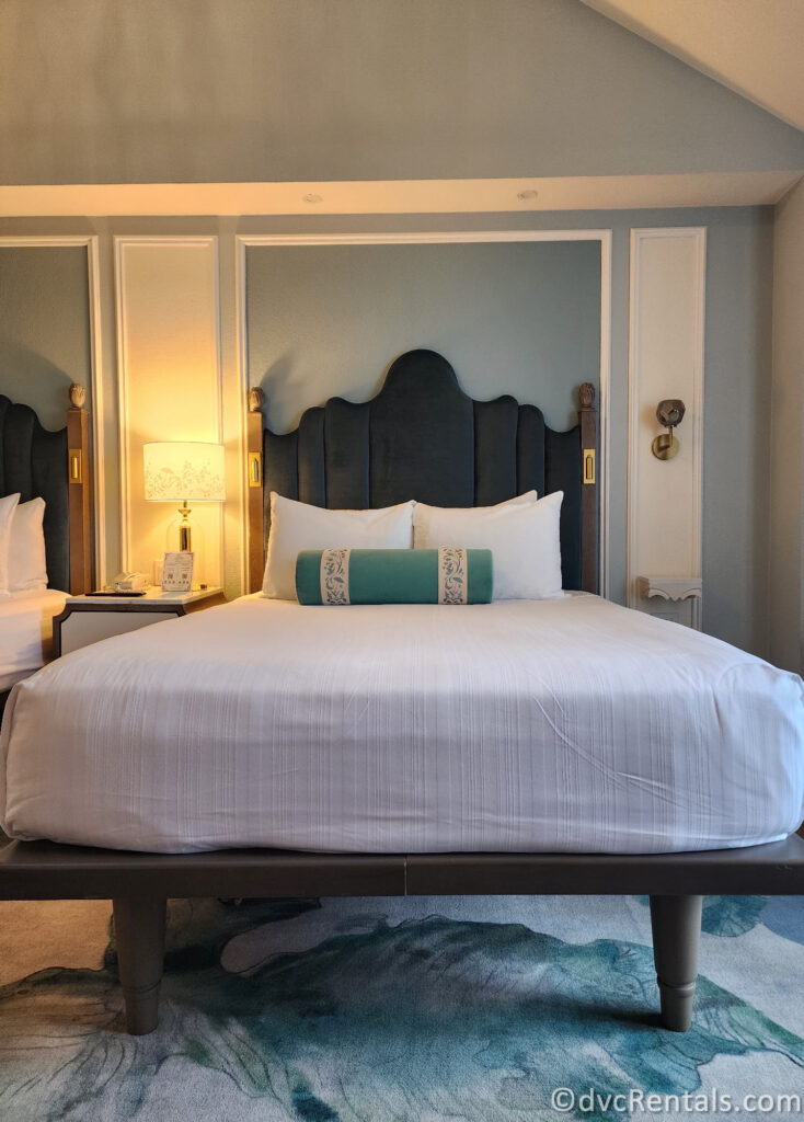 Queen-sized bed in the Resort Studio. The bed is covered in white linens and a teal decorative pillow.