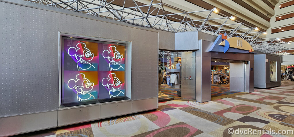 Front of Bay View Gifts at Bay Lake Tower featuring a large display of Mickey Mouse pop art in neon colors. The store has a modern design with glass windows and a metal exterior.