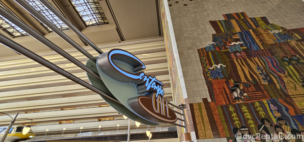 Contempo Cafe sign at Disney's Contemporary Resort. The sign is illuminated in blue neon and hangs from the ceiling. Behind the sign is a large, colorful mosaic.