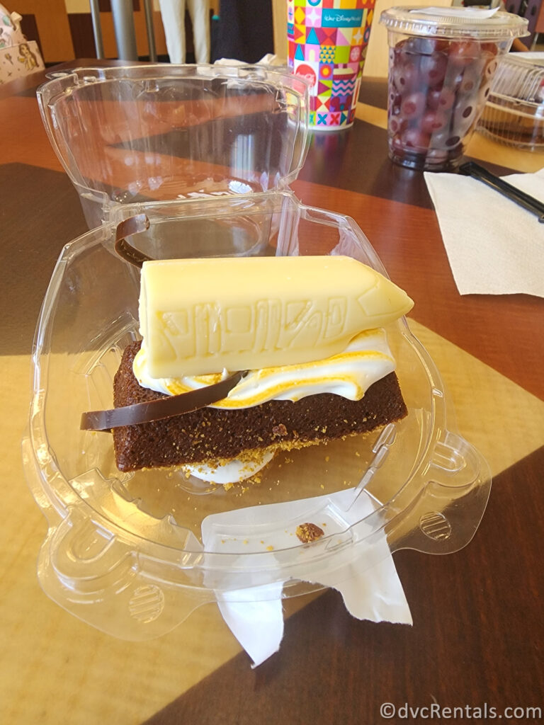 Chocolate brownie topped with a white chocolate monorail car sitting in a plastic container.