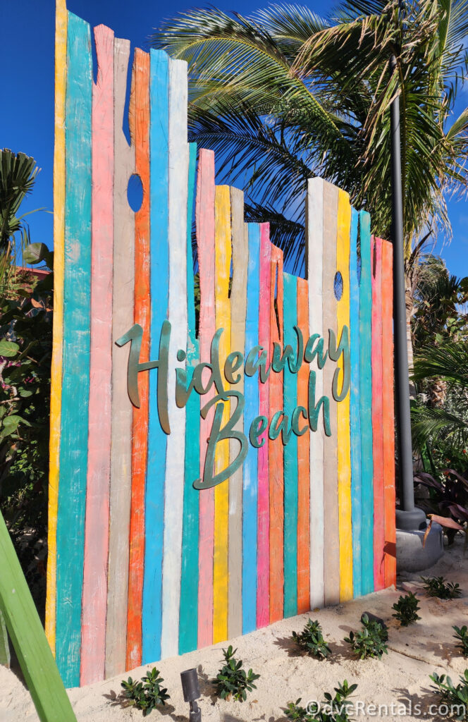 The words "Hideaway Beach" are written in teal cursive on top of colorful pieces of wood.