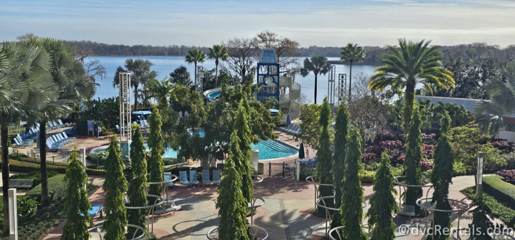 Exterior ground of Bay Lake Tower. Lots of palm trees surround the pool area, with Bay Lake in the background of the photo.