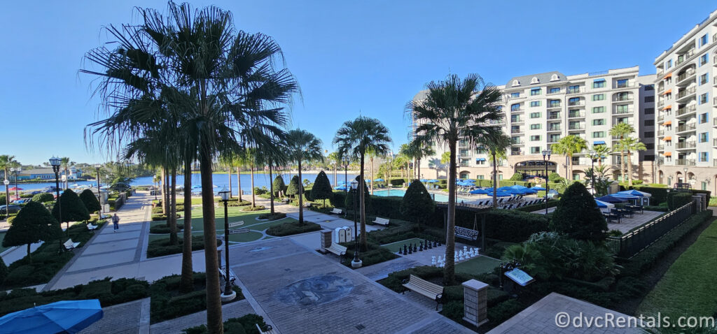 A scenic view of Disney's Riviera Resort. The image shows a pool area with palm trees, lounge chairs, and umbrellas.