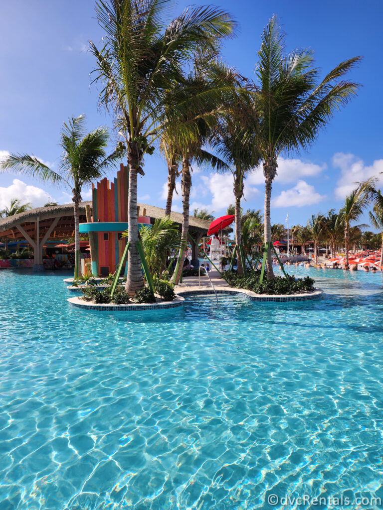 Bright blue waters of the pool at Hideaway Beach. There is a little island with a DJ booth in the middle of the pool.