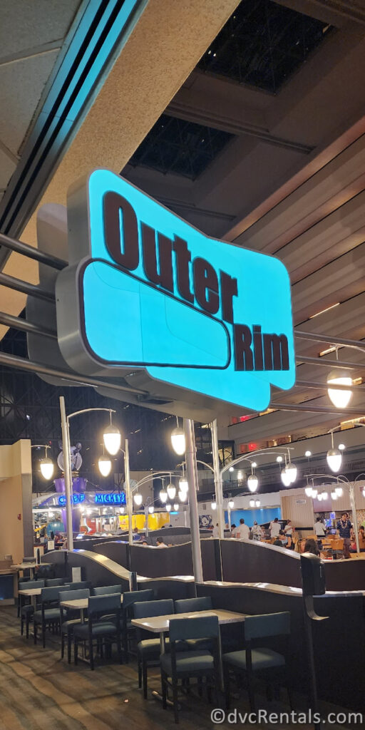 Entrance to the Outer Rim Lounge. The sign to the lounge is neon blue, with black lettering.