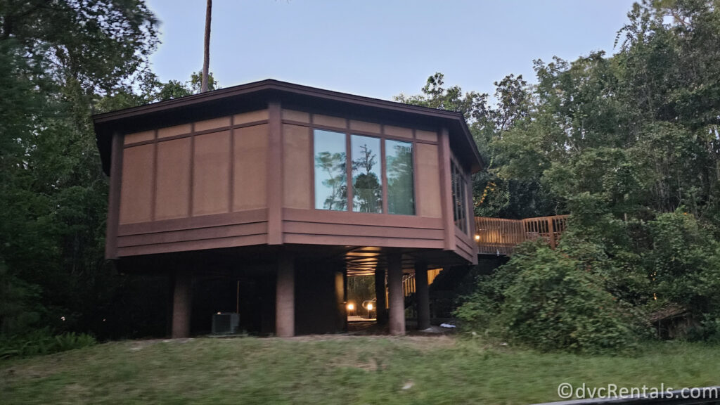 A Treehouse at Disney's Saratoga Springs. The villa is elevated on stilts and has a hexagonal shape with large windows overlooking the surrounding forest.