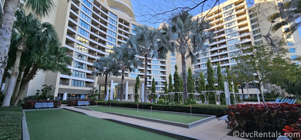 Backside of Bay Lake Tower. The hotel towers are visible on either side of the image, with palm trees and a bocce ball court in the foreground.