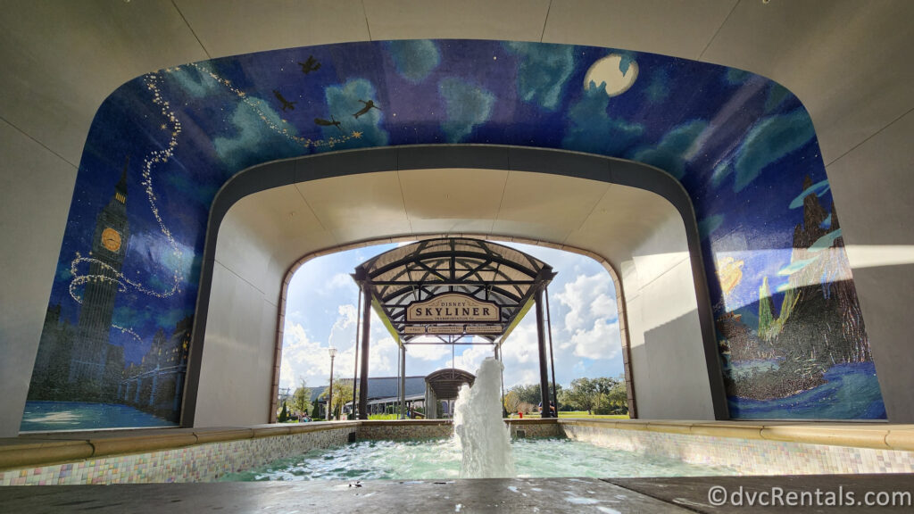 A photo of the Skyliner station entrance at Disney's Riviera Resort. A large, colorful mosaic depicting Peter Pan covers the archway above the entrance.