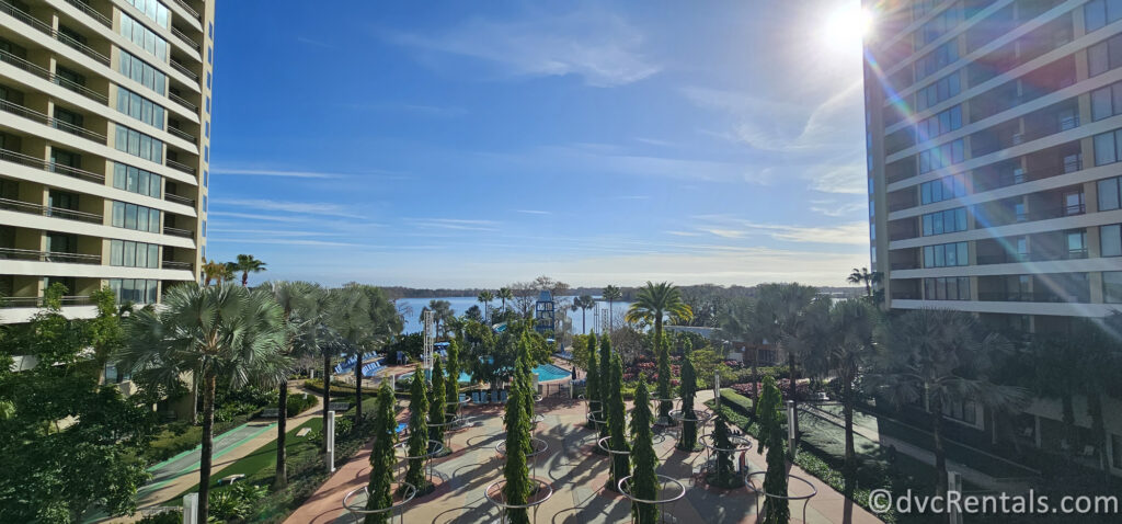 Exterior ground of Bay Lake Tower. Lots of palm trees surround the pool area, with Bay Lake in the background of the photo.