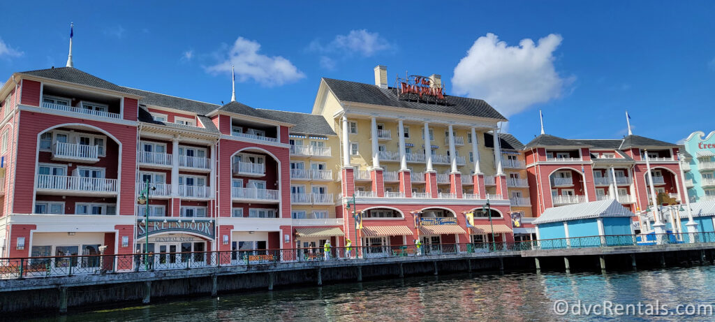 A colorful and vibrant view of Disney's Boardwalk Resort. The resort's buildings are painted in various shades of red, yellow, and blue, and feature balconies and arched windows.