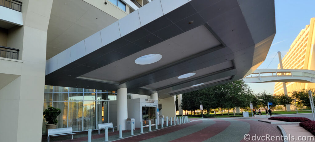 Exterior of Bay Lake Tower at Disney's Contemporary Resort. The entrance is illuminated by several circular lights, and there is a glass door leading inside.