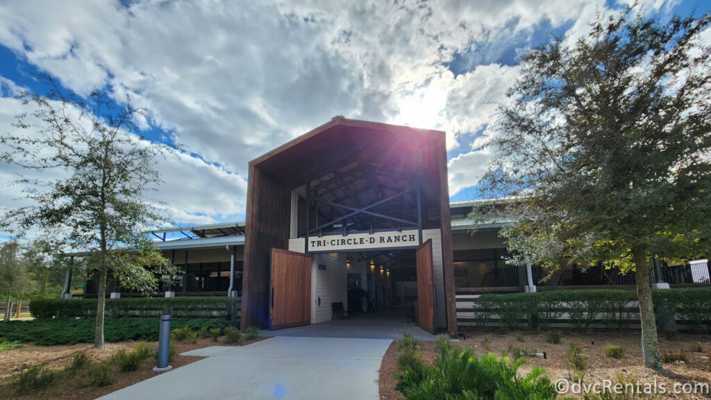 A large, wooden entranceway to Tri-Circle D Ranch. The entrance has a rustic appearance with exposed beams and a pitched roof.