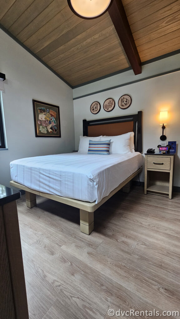 Bedroom in the cabin with a large bed featuring a white comforter and a striped pillow. The bed has a wooden headboard and frame.