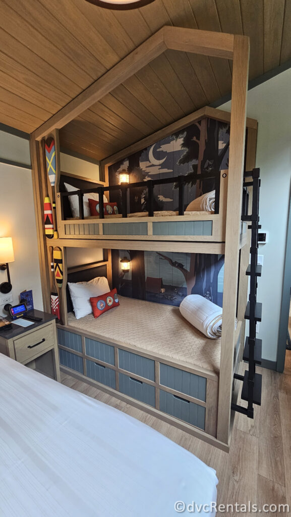 Bunk beds in the bedroom featuring a lower bunk and two upper bunks. The bunk bed has a wooden frame and is decorated with woodsy artwork.