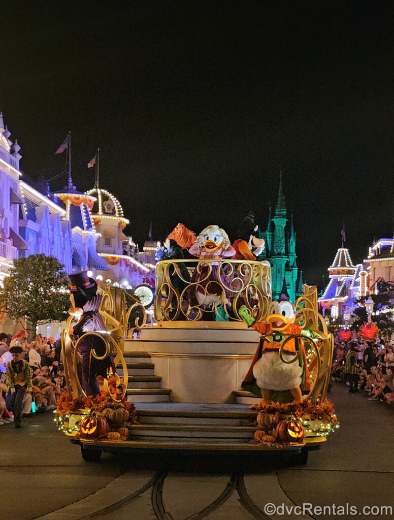 A parade float featuring Mickey Mouse as a vampire and Donald Duck as a superhero. At the top of the float, Daisy Duck, Minnie Mouse, and Clarabelle Cow are dressed as the Sanderson Sisters from Hocus Pocus.