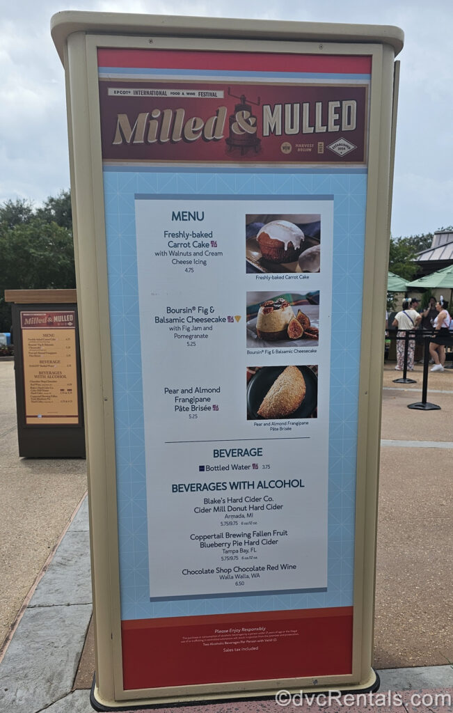 The red, white, and blue menu board for the Milled & Mulled booth at the EPCOT International Food & Wine Festival. There are photos and descriptions of the food and drink options, as well as pricing displayed on the menu board.