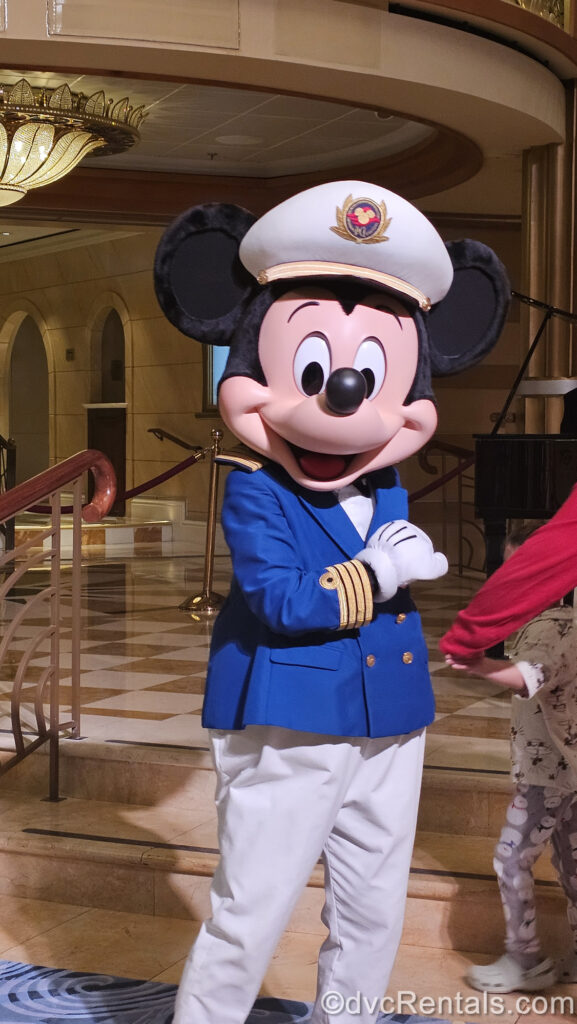 Mickey Mouse wears a blue and white ship captain costume while greeting guests on a Disney Cruise Ship.