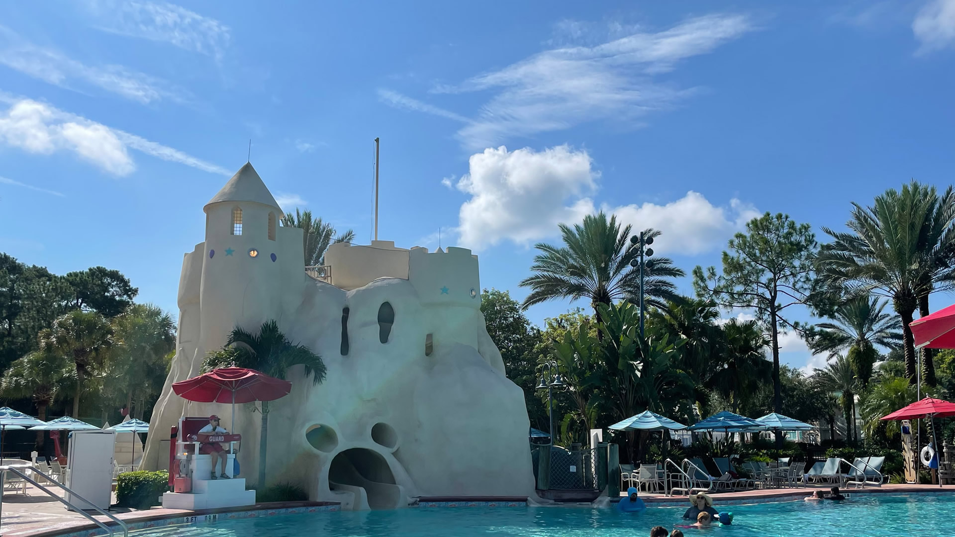 The Sandcastle Pool at Disney’s Old Key West Resort is seen on a sunny day. There is a large beige structure made to look like a giant sandcastle that holds the waterslide, and the opening is shaped like Mickey Mouse’s head.