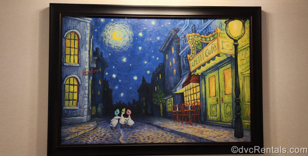 A painting of 3 geese wearing pastel bonnets and walking along a French cobblestone road under a blue, starry sky is displayed in a black frame at Disney’s Riviera Resort.