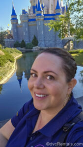 DVCR team member Stacy poses for a smiling selfie in front of Cinderella Castle during a sunny day at Magic Kingdom.