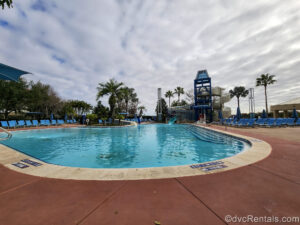 The Bay Cove Pool at Bay Lake Tower at Disney’s Contemporary Resort. There is a tall waterslide tower on the far side that features a Mickey Mouse silhouette and a winding staircase leading up to it.