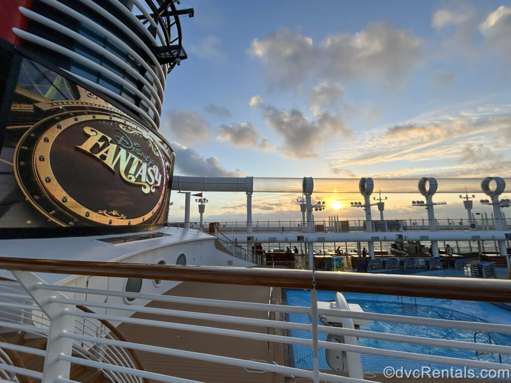 The sun rises over the exterior decks and pool of the Disney Fantasy. The ship’s logo is seen displayed on the giant funnel screen as the morning sky brightens.