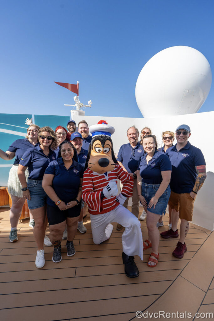 Several David’s Vacation Club Rentals team members pose with Goofy during a special meet and greet event on the exterior deck of the Disney Fantasy.