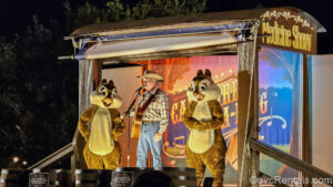 Chip ‘n’ Dale and their cowboy friend perform a campfire sing-along on a stage made from an old-fashioned covered wagon at night at Disney’s Fort Wilderness Resort.