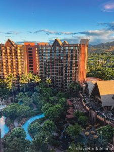 The pool, grounds, and buildings of Disney’s Aulani Resort in Hawaii are seen from a high floor balcony under a sunny, blue sky.