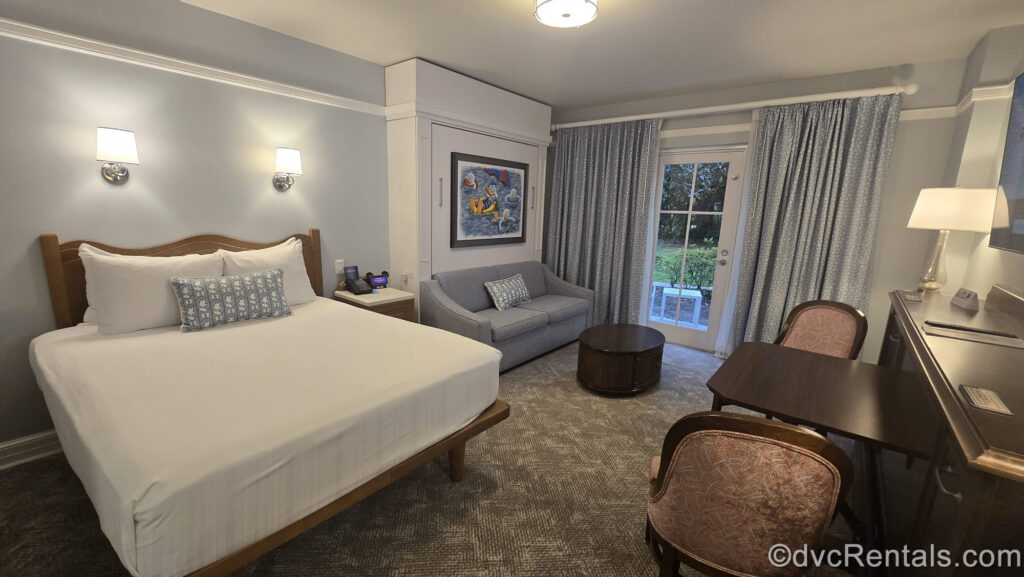 A Deluxe Studio Resort View at Disney’s Beach Club Villas. The room is decorated with soft blues and accents and artwork featuring Donald and Daisy Duck.