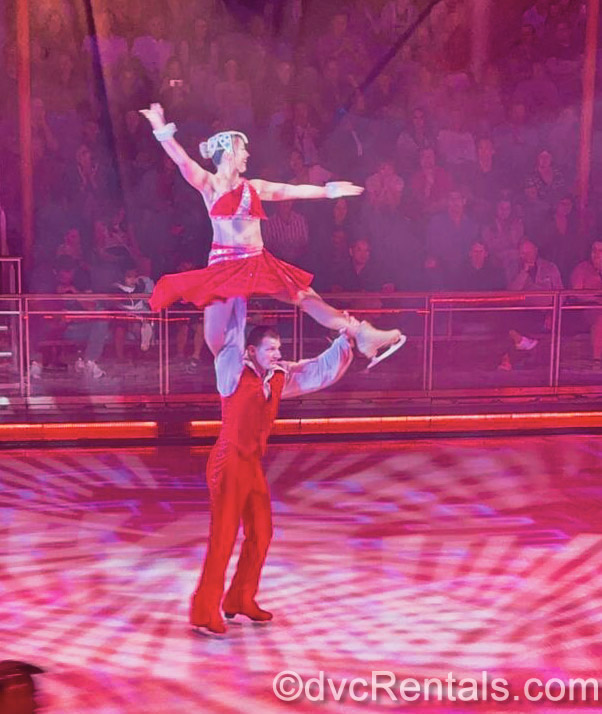 Ice skaters in red costumes perform a lift maneuver during a show at the Studio B Ice Rink on the ship.