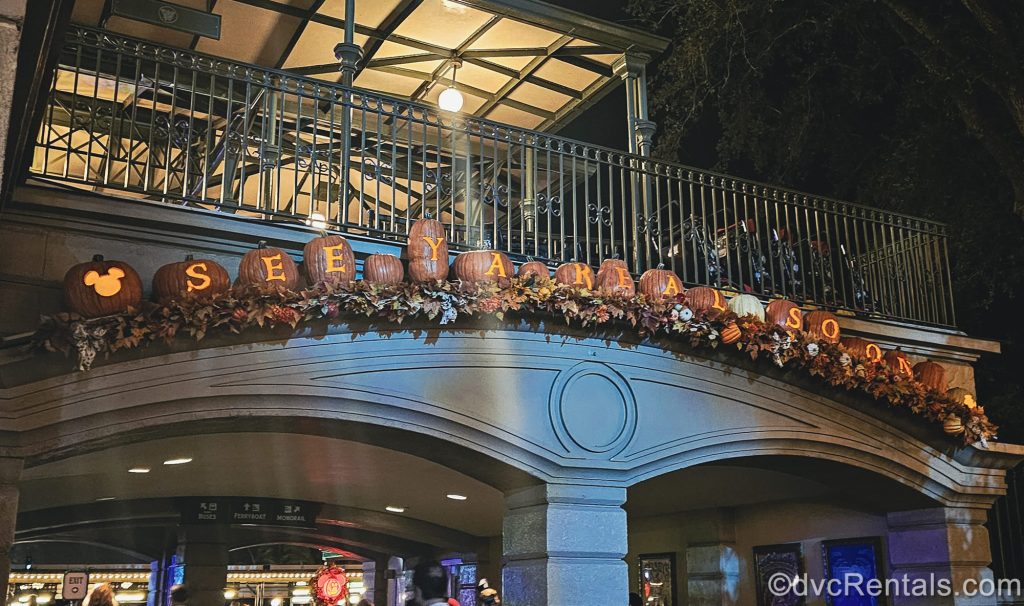 Carved pumpkins spelling out “See Ya Real Soon” are lit up and displayed over the exit from the Magic Kingdom.