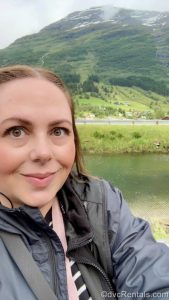 DVCR Team Member Stacy smiles in a selfie in front of a snow-capped mountain landscape in Olden, Norway.