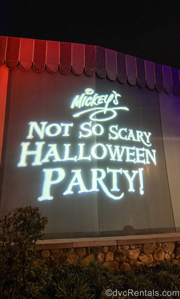 “Mickey’s Not So Scary Halloween Party!” is displayed in a white light projection on a wall at Magic Kingdom.