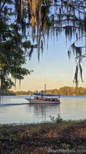 A white boat with a blue canopy carries guests across Bay Lake from Disney’s Wilderness Lodge to the Magic Kingdom, as seen from the resort.