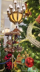 The nautical-themed ornaments on a Christmas tree at Disney’s Beach Club Villas are seen with the lobby’s gingerbread carousel display visible in the background.
