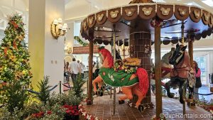 A large gingerbread carousel is displayed along with a Christmas tree with nautical-themed ornaments, and other seasonal plants in the lobby of Disney’s Beach Club Villas.